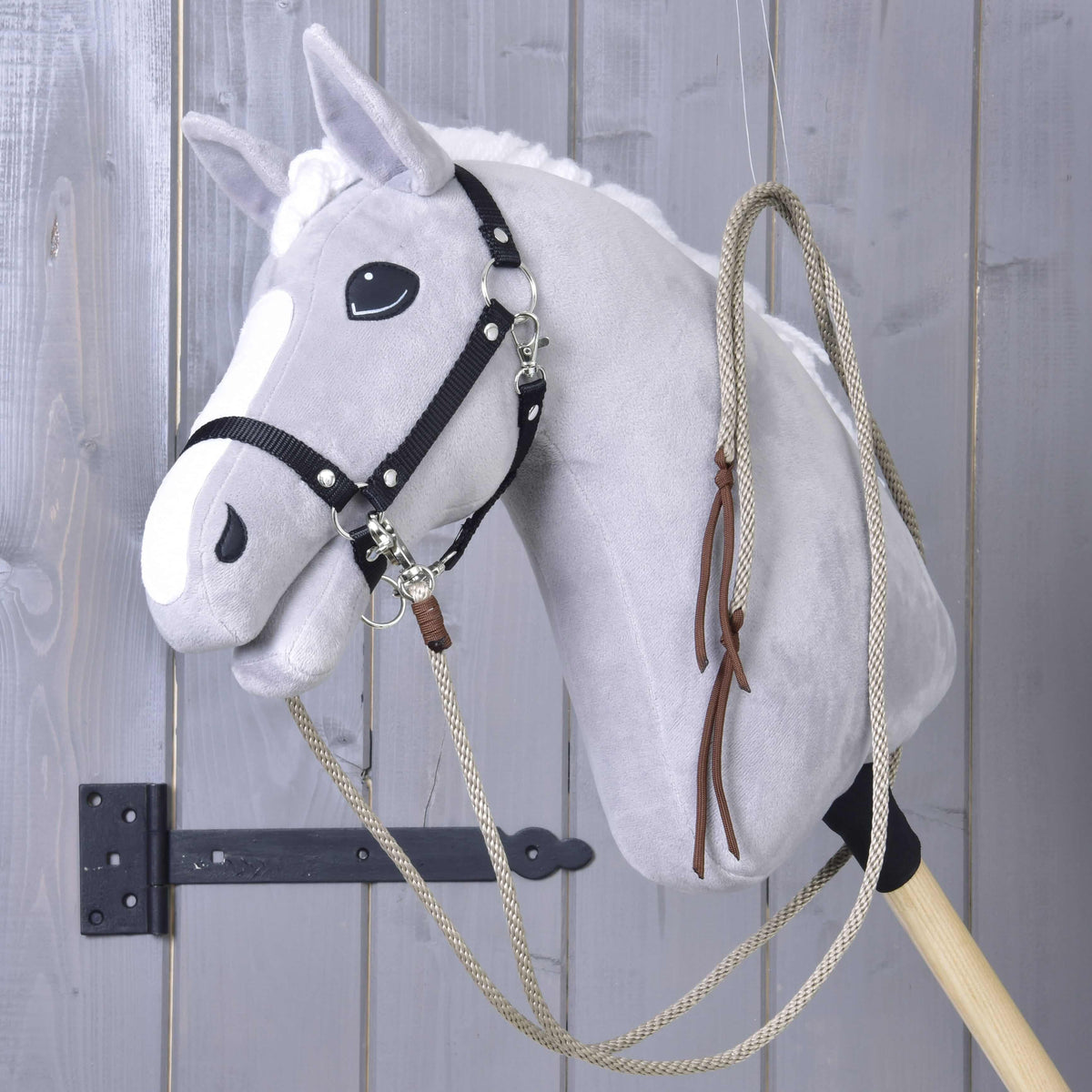 Beige western reins looped over the neck of a grey Hobby Horse, the brown leather tie ends hanging down the side