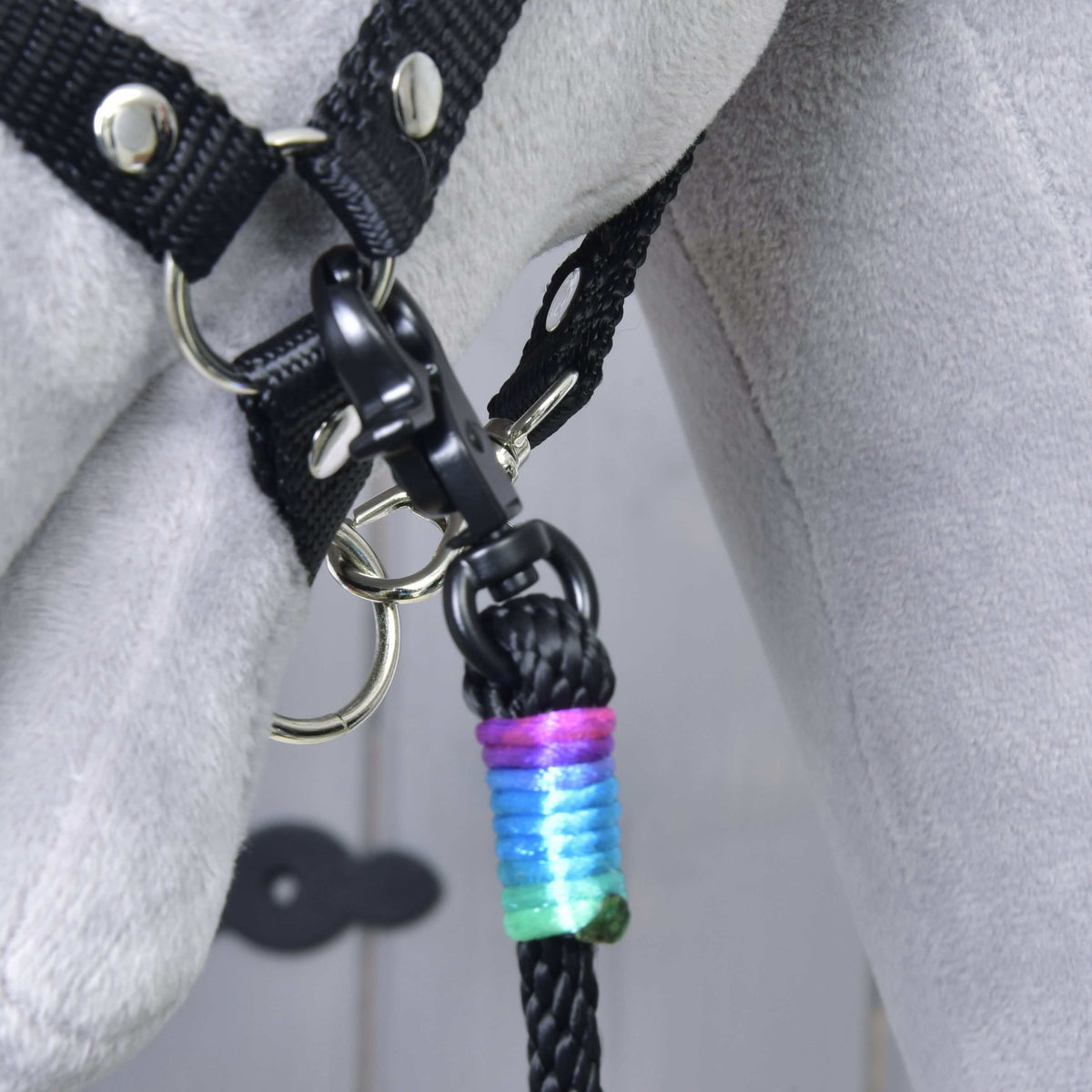 Close-up of a black snap hook on the halter ring and the purple, blue and green thread wrap on the black rope