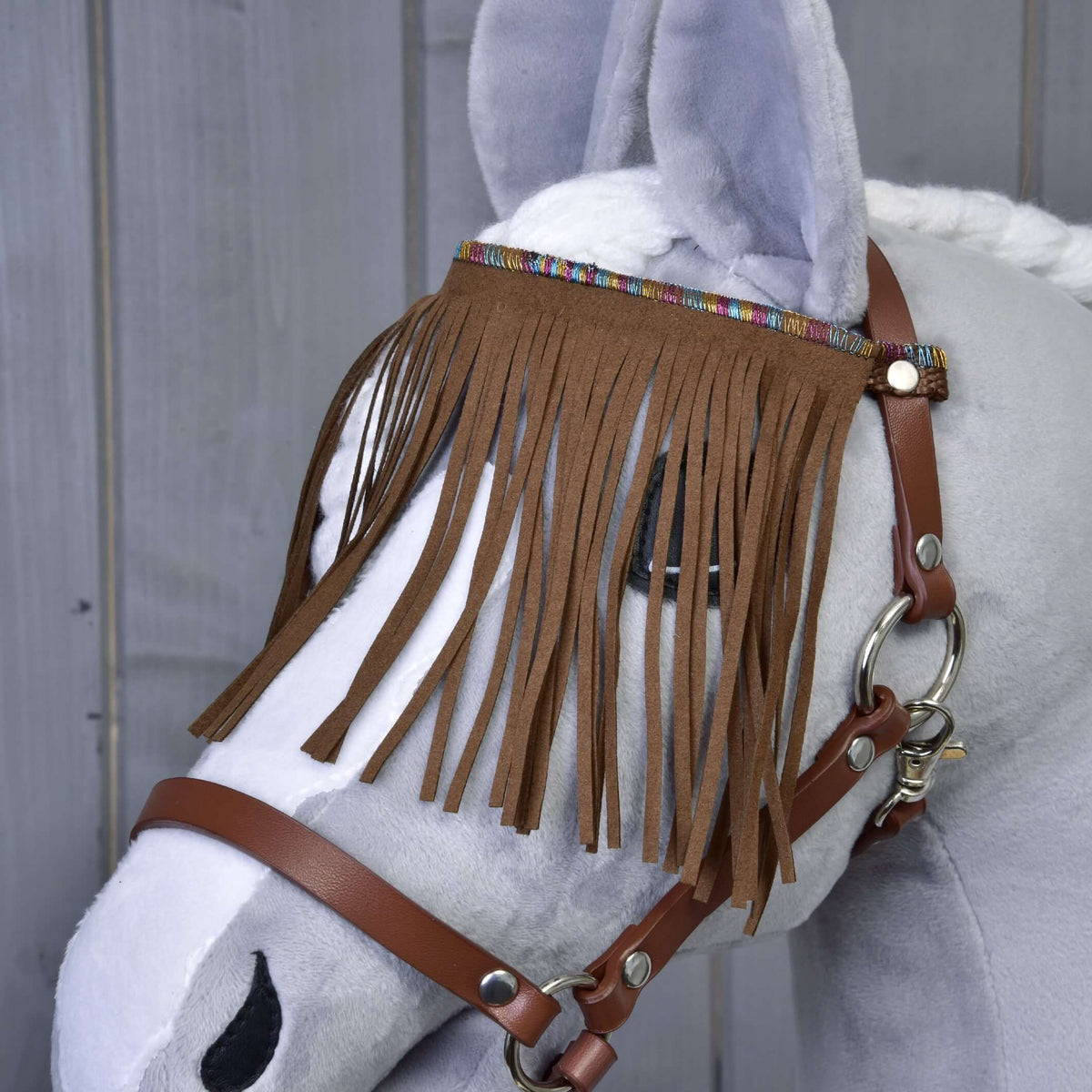 Bližnji posnetek rjavega čelnika z resicami in pisanim tkanim trakom na rjavi Hobby Horse oglavki