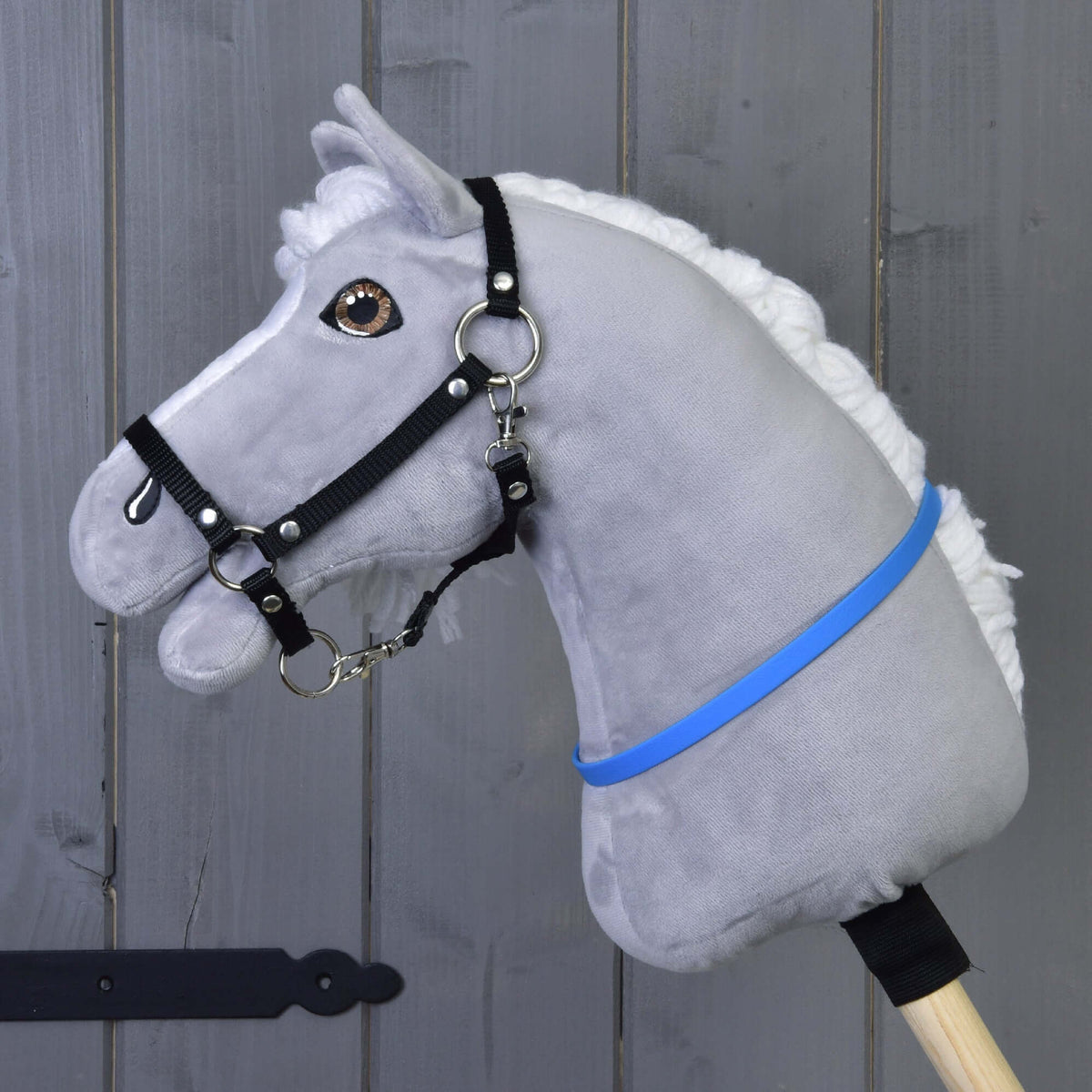 Siv plišast Hobby Horse konj z belo grivo in črno oglavko nosi živo moder vratni obroč (cordeo) okoli vratu